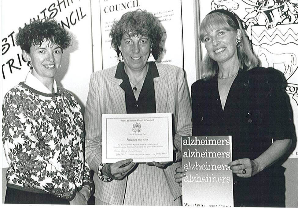 Early 1990s black and white image of three women standing in a row with documents from charity's foundation