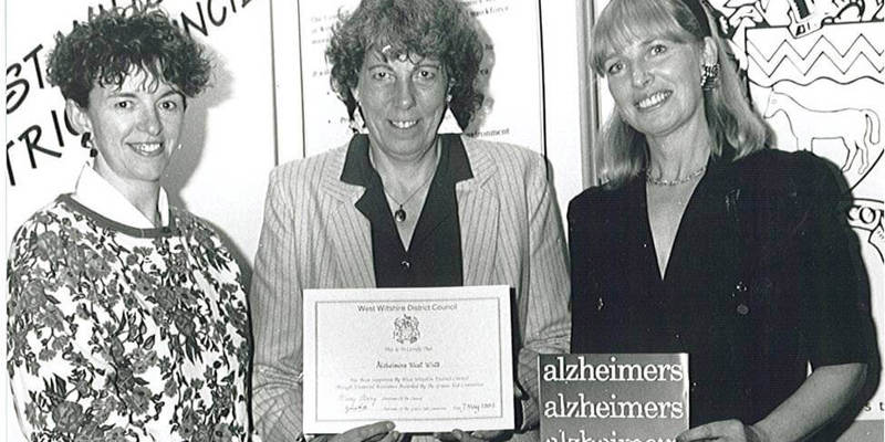 Early 1990s black and white image of three women standing in a row with documents from charity's foundation