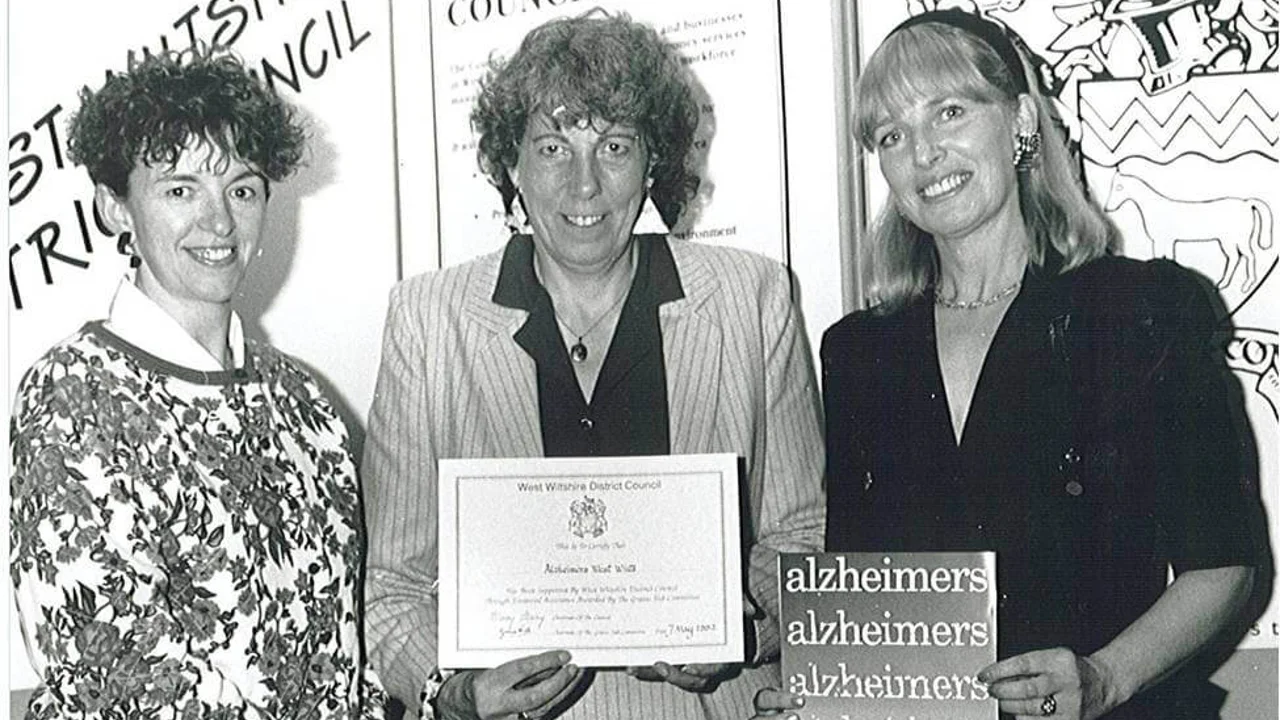 Early 1990s black and white image of three women standing in a row with documents from charity's foundation
