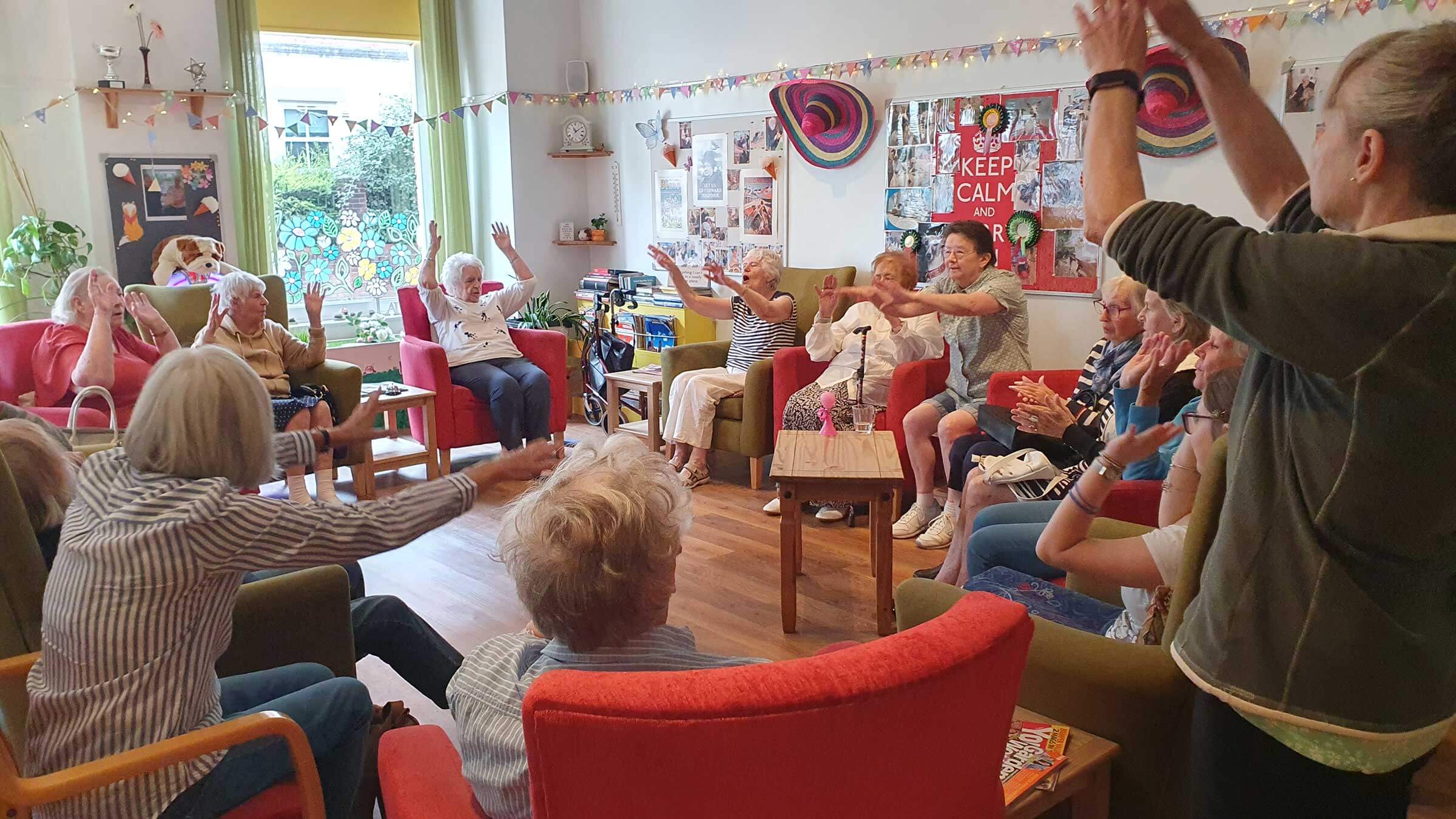 A group of men and women sitting in a group raising their arms together at Mill Street Club 