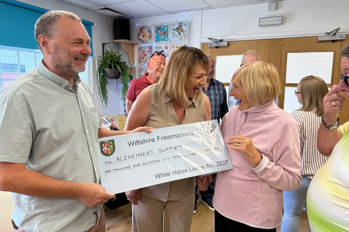 A very happy picture showing a man presenting a cheque to Old Silk Works club with Louise the Manager and a member laughing and holding the cheque. Behind are other staff and members of the club