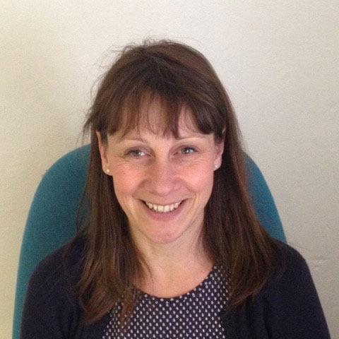 headshot of Tara wearing a polka dot blue and top and smiling at the camera