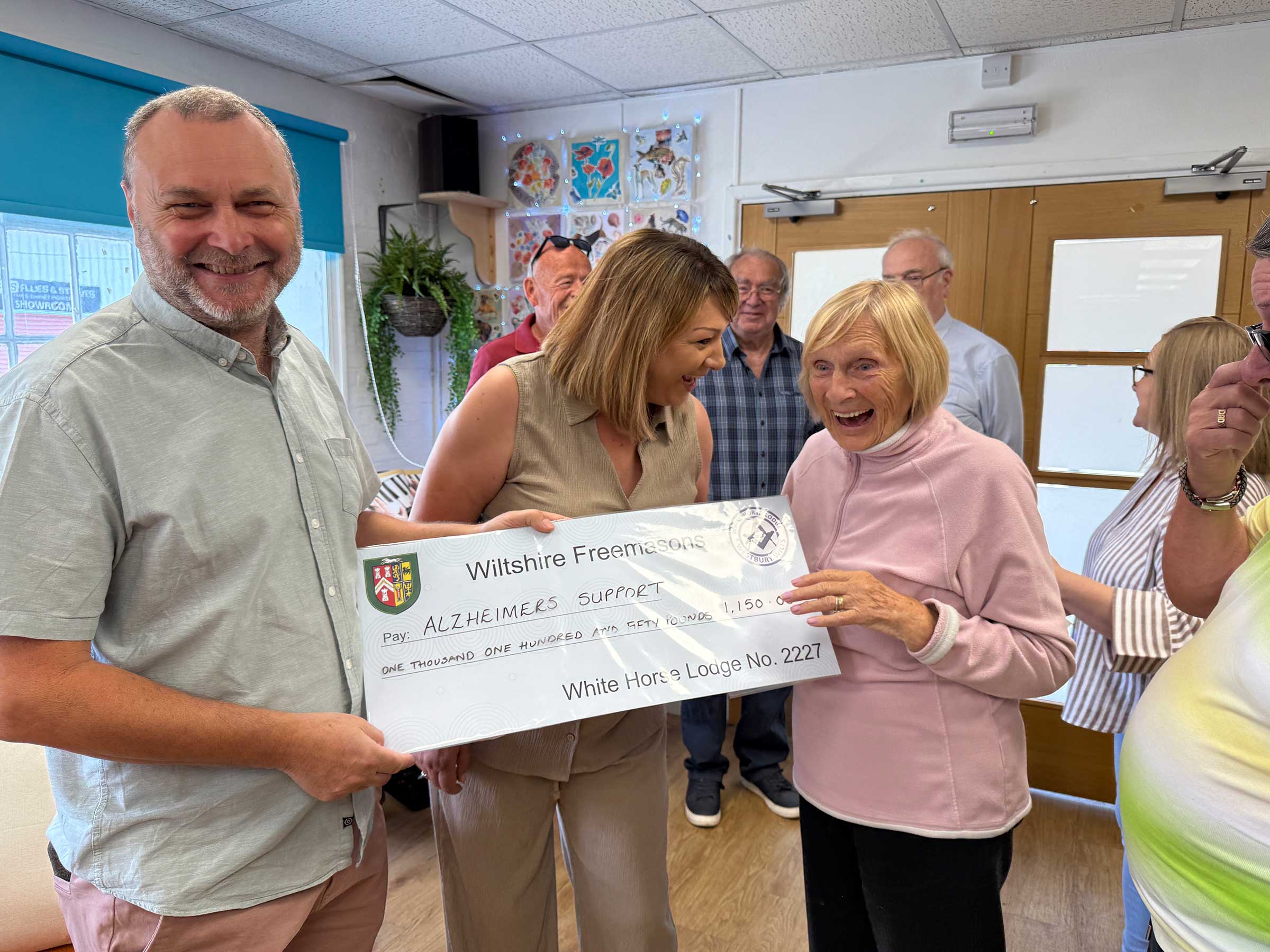 A very happy picture showing a man presenting a cheque to Old Silk Works club with Louise the Manager and a member laughing and holding the cheque.  Behind are other staff and members of the club 