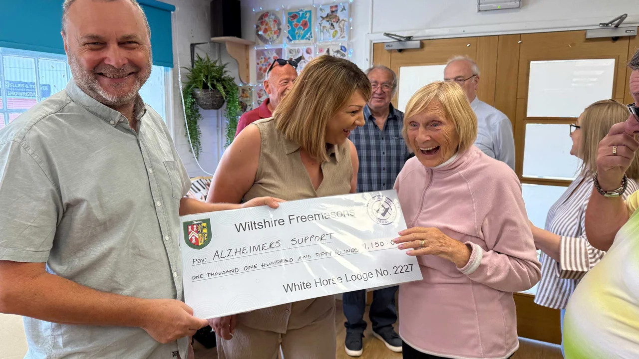 A very happy picture showing a man presenting a cheque to Old Silk Works club with Louise the Manager and a member laughing and holding the cheque. Behind are other staff and members of the club