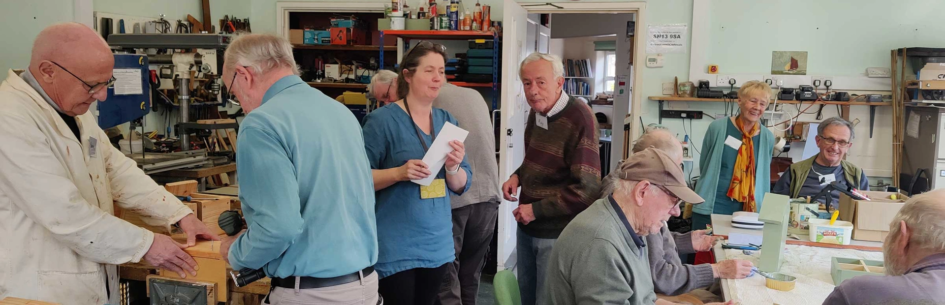 Groups of mostly older men taking part in practical woodworking activities and using tools inside the memory shed building Groups of mostly older men taking part in practical woodworking activities and using tools inside the memory shed building