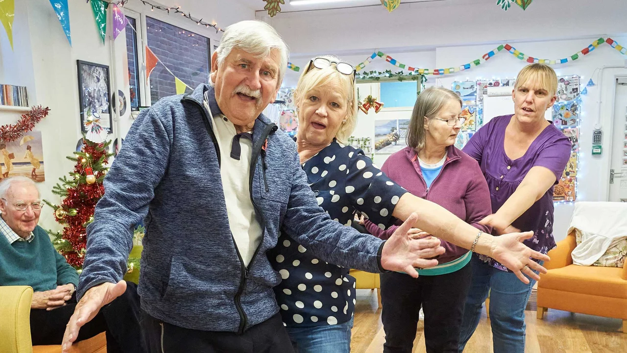 A man and three ladies dancing and waving in Mill Street Club with Christmas decorations
