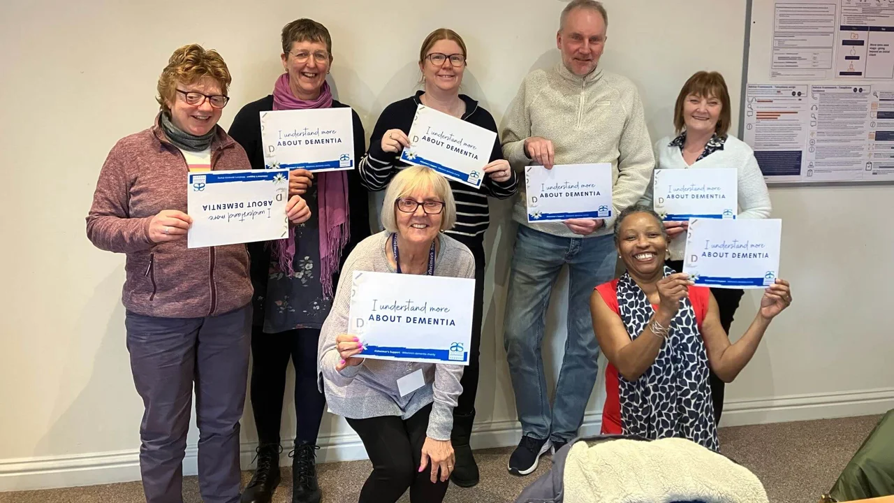 Trainer Annie Clayton with a group of six Understanding Dementia champions holding 'I understand more' cards