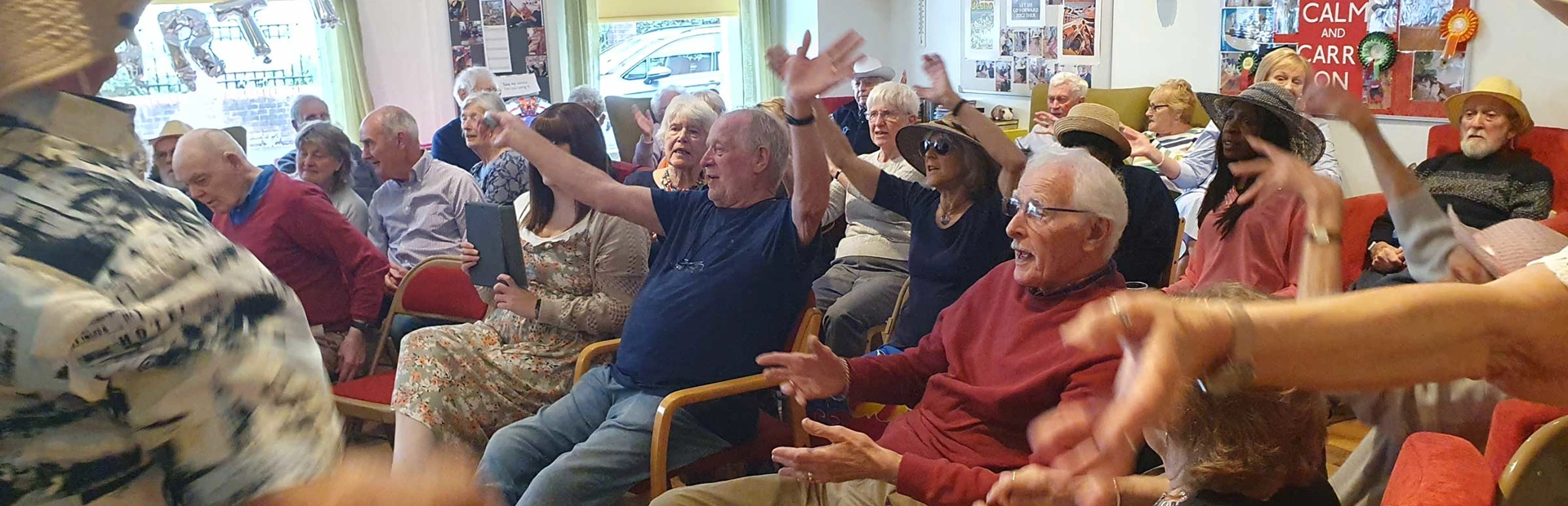About 20 people sitting, clapping and waving their arms as they listen to music at the party. About 20 people sitting, clapping and waving their arms as they listen to music at the party.