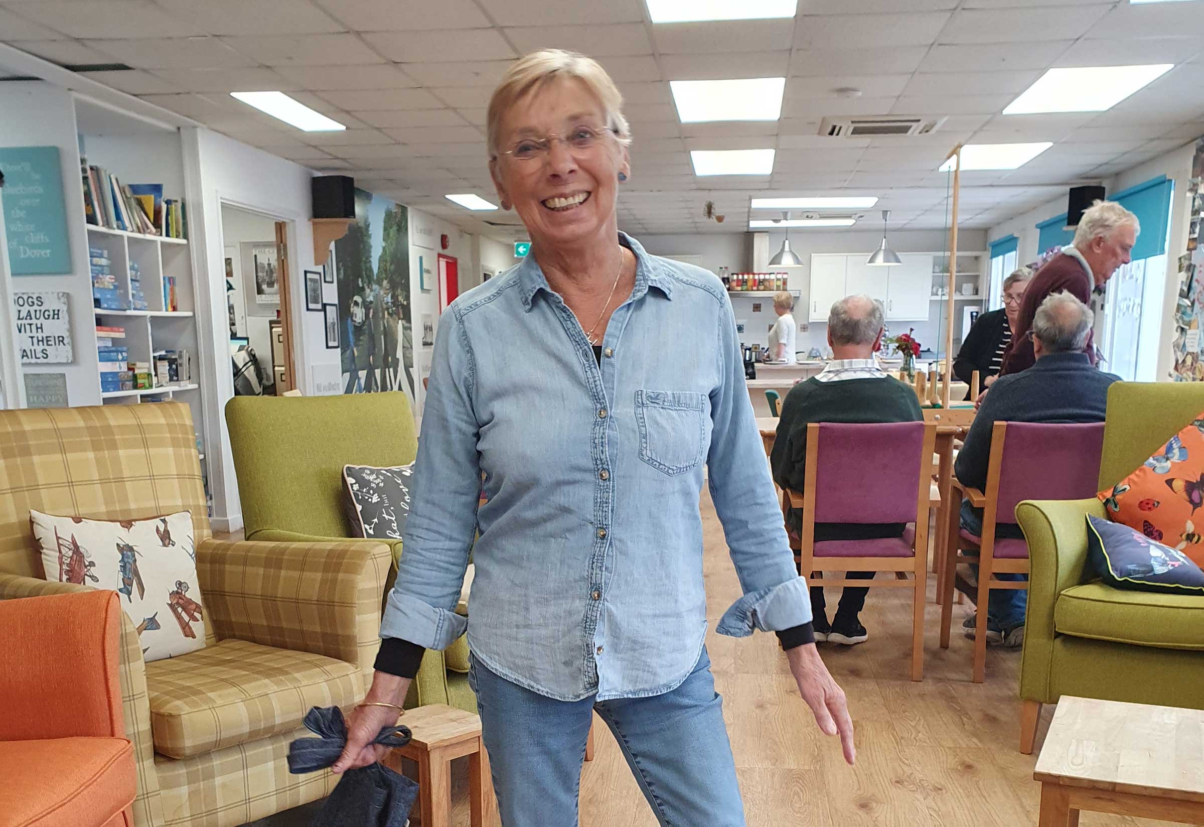 A smiling lady, Hilary wearing a blue denim shirt and blue jeans standing in Old Silk Works club 