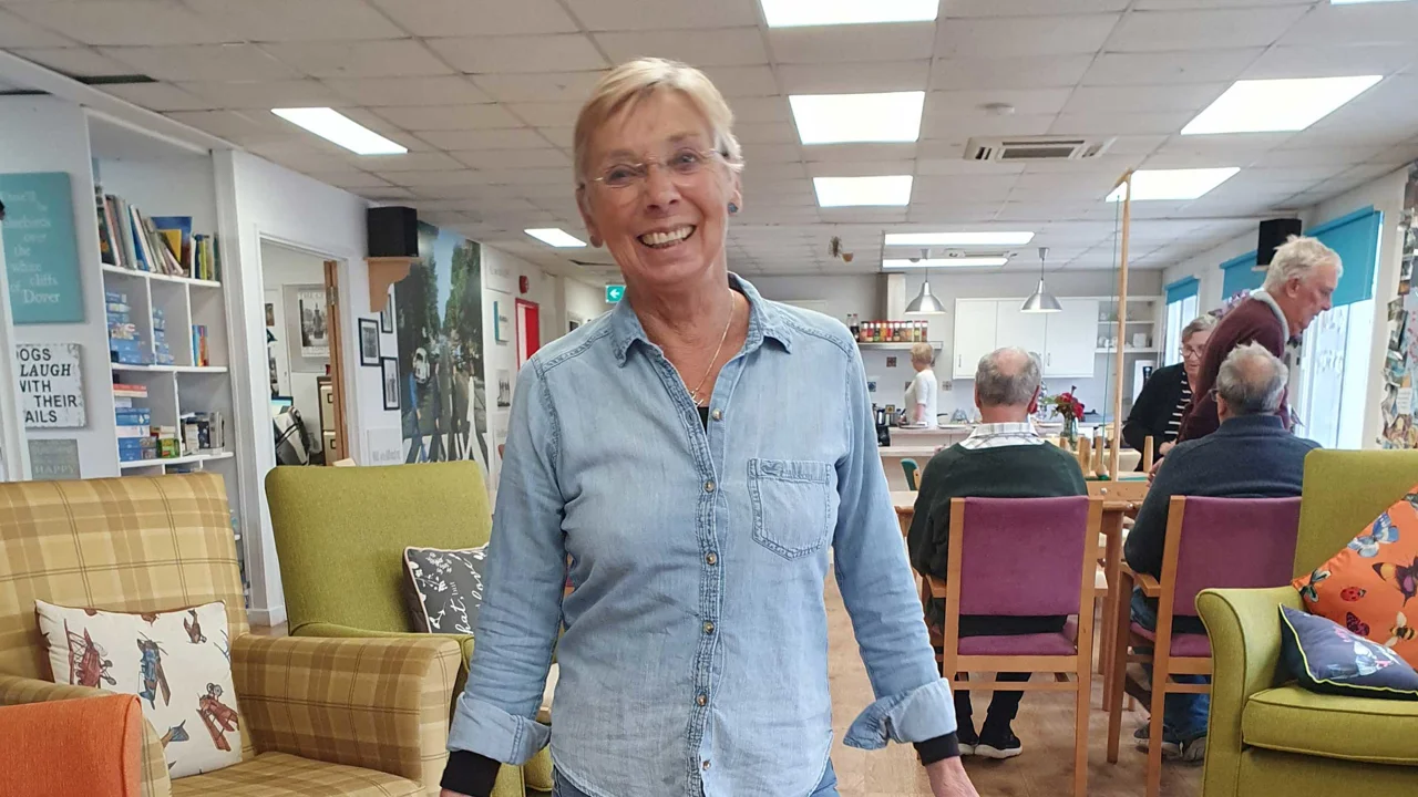 A smiling lady, Hilary wearing a blue denim shirt and blue jeans standing in Old Silk Works club