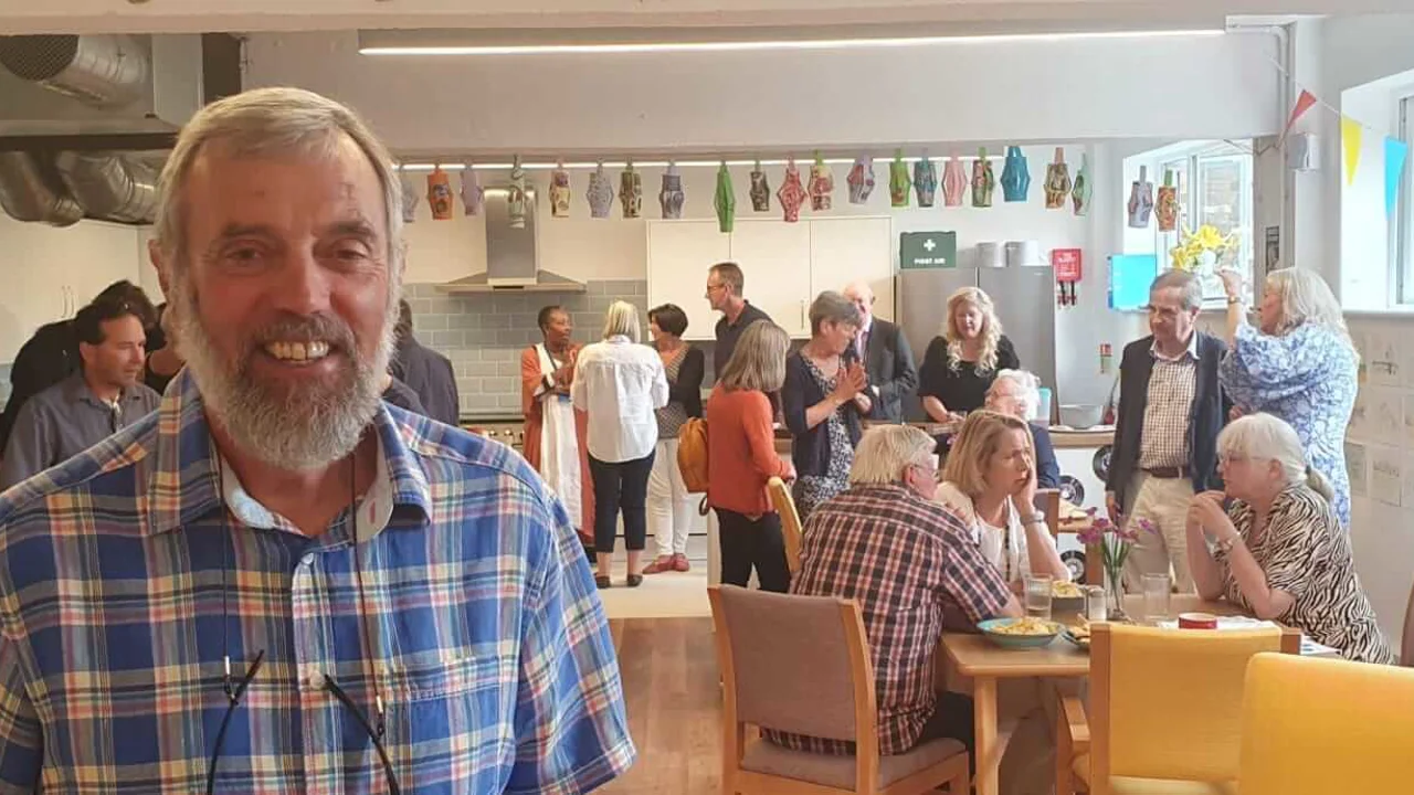 A bearded man with a checked shirt looking at us with a group of people chatting at a party behind him at Scots Lane Club