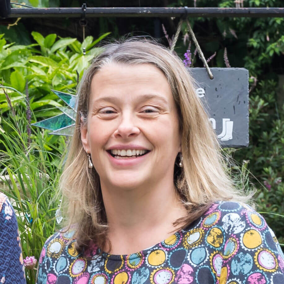 Karen wearing a brightly coloured top, smiling at the camera, outside