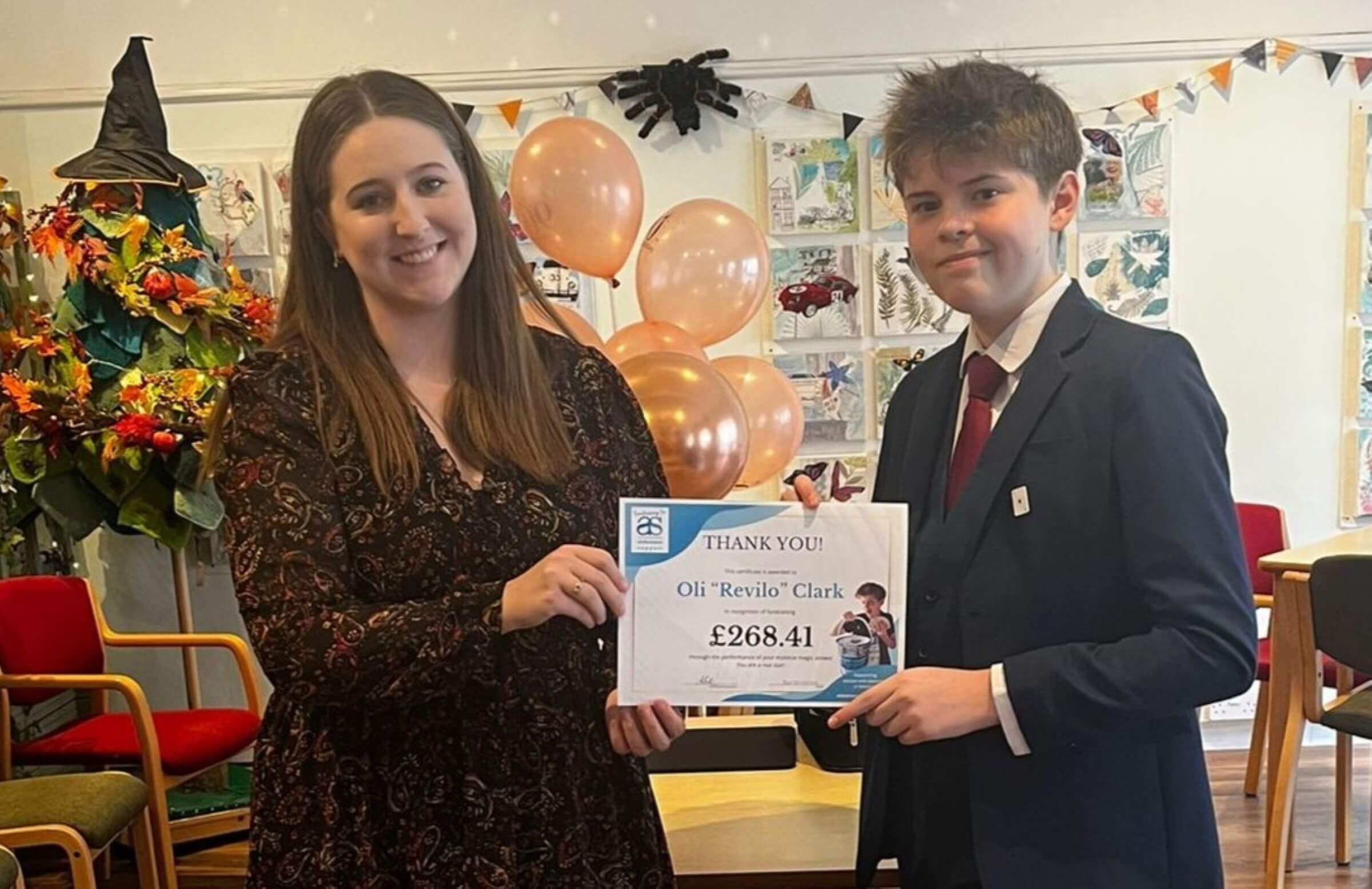 Beyond Dementia staff member Alex presenting an achievement certificate to fundraiser Oli for raising £268.41