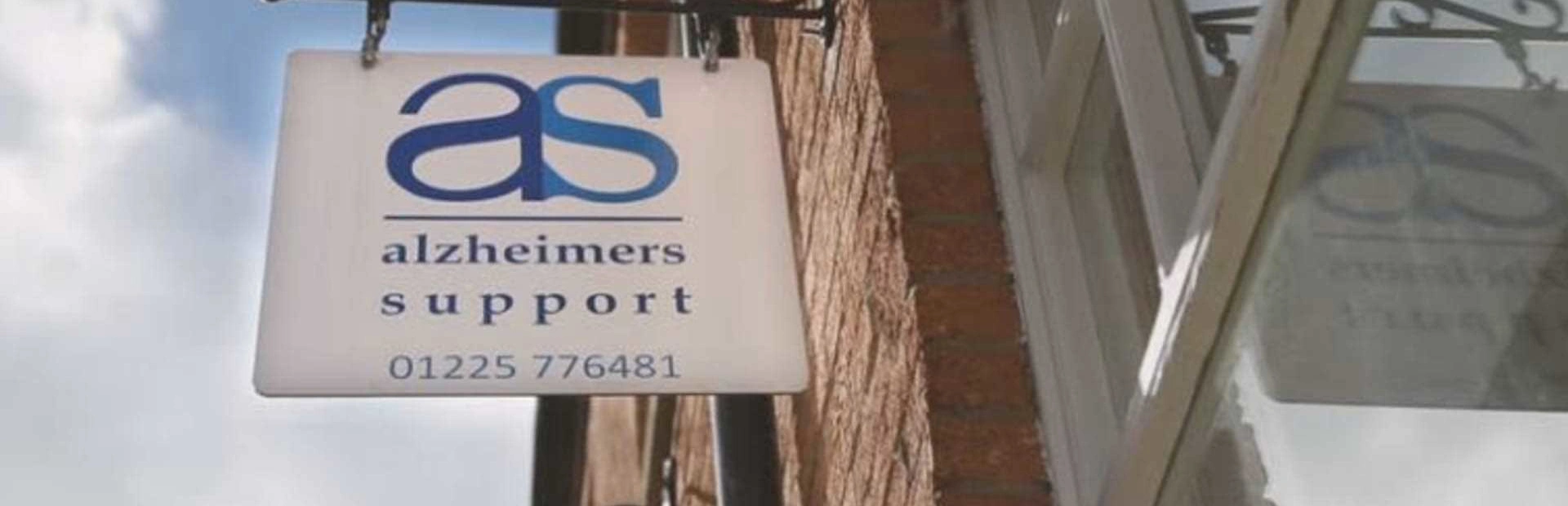This is a picture looking up at Alzheimers Support sign hanging outside Trowbridge office on the brick wall This is a picture looking up at Alzheimers Support sign hanging outside Trowbridge office on the brick wall