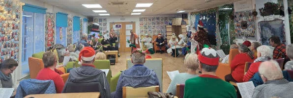A wide angle shot of Old Silk Works club showing a group of people from behind, watching the Nativity play with the actors at the far end