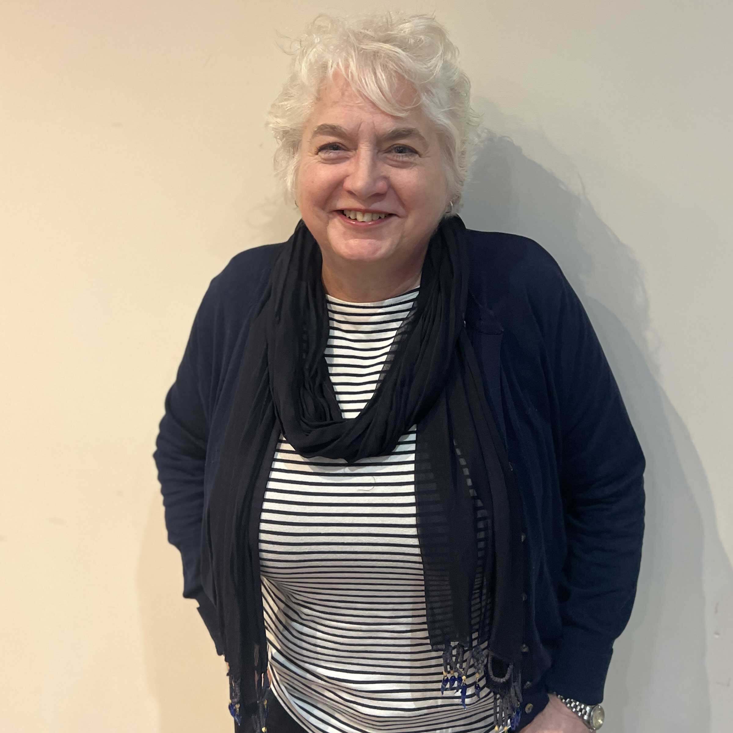 Head and shoulders of Sue wearing a stripey blue and white top and smiling