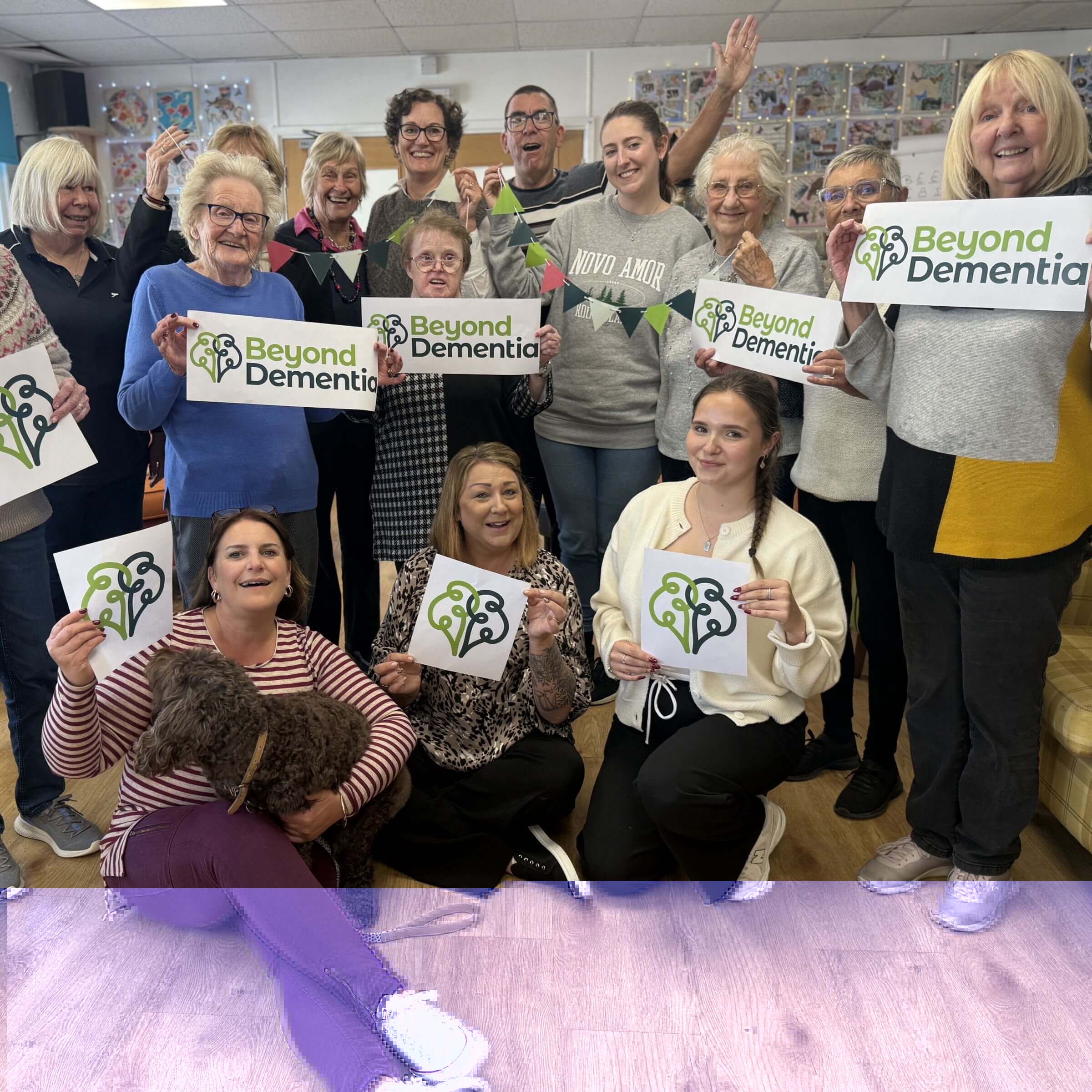 A group of day club member and day club staff holding Beyond Dementia logo banners