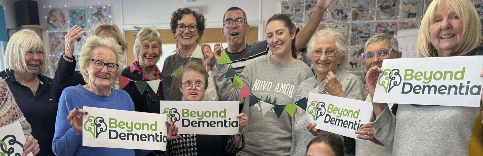 A group of day club member and day club staff holding Beyond Dementia logo banners A group of day club member and day club staff holding Beyond Dementia logo banners