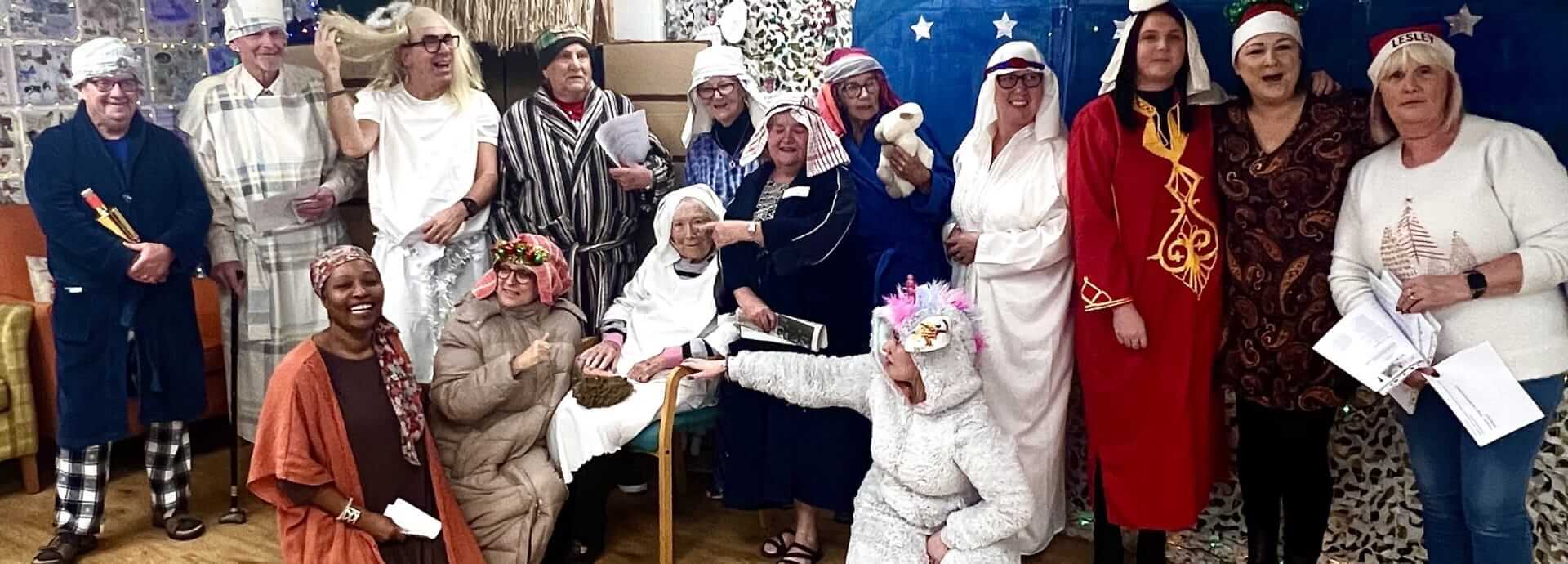 Old Silk Works Nativity scene, fifteen people standing together in a group, dressed in nativity costumes and with props all smiling.