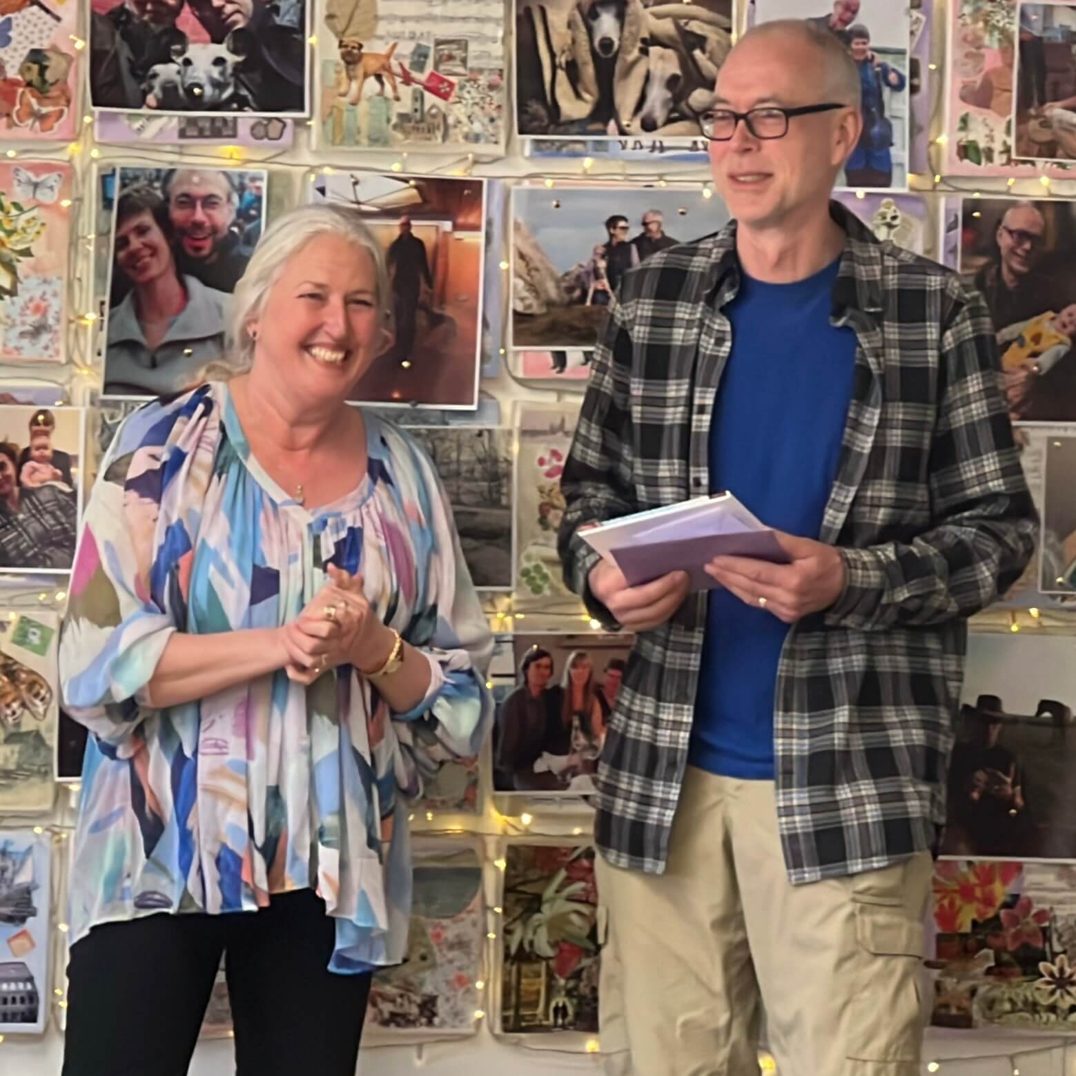 Grant smiling alongside CEO Sarah as he receives farewell cards and thanks. Both standing in front of colourful artwork at a day club