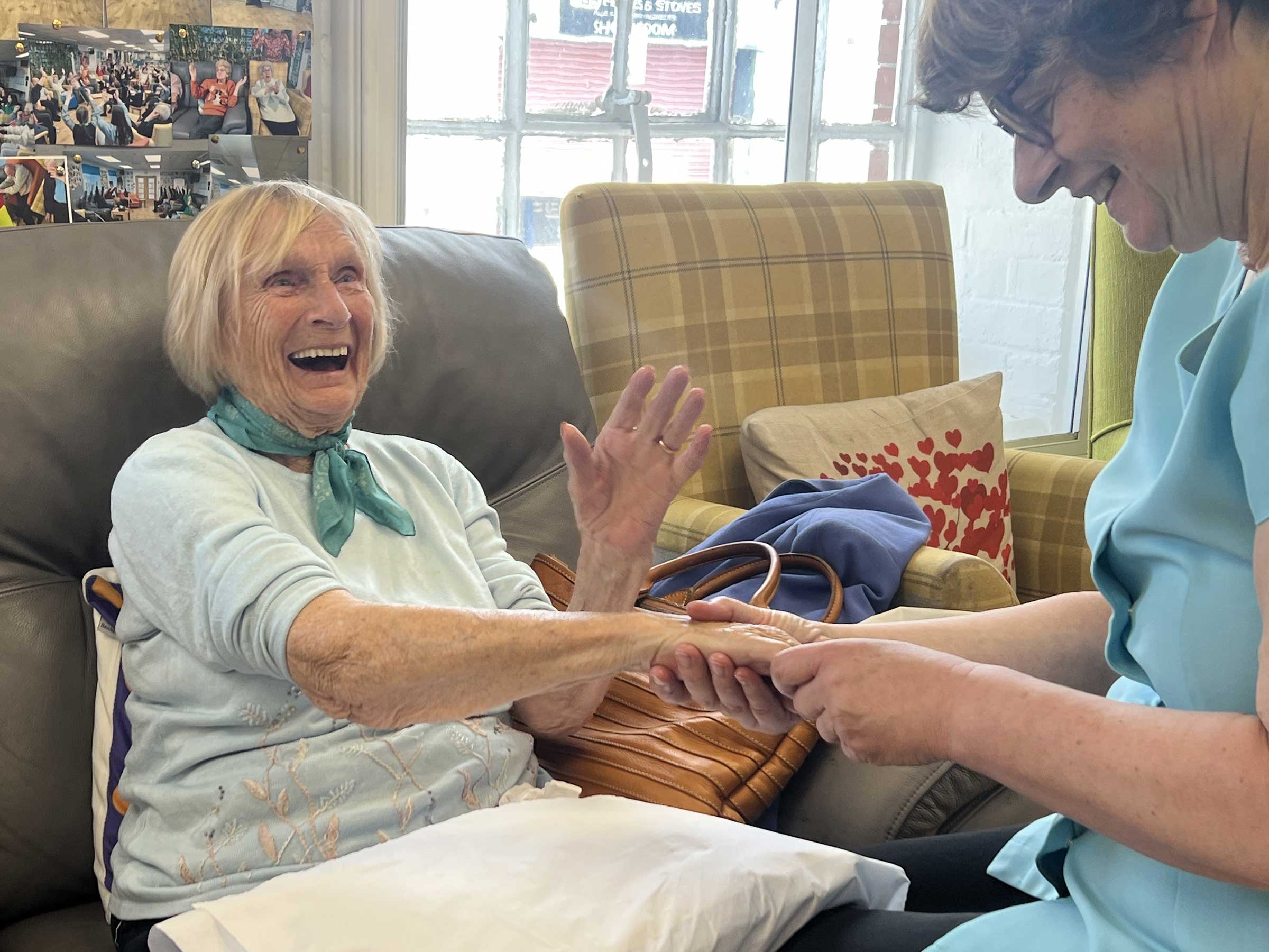 One lady sitting having her hand massaged, smiling and laughing with another lady at the side massaging her hand at Old Silk Works