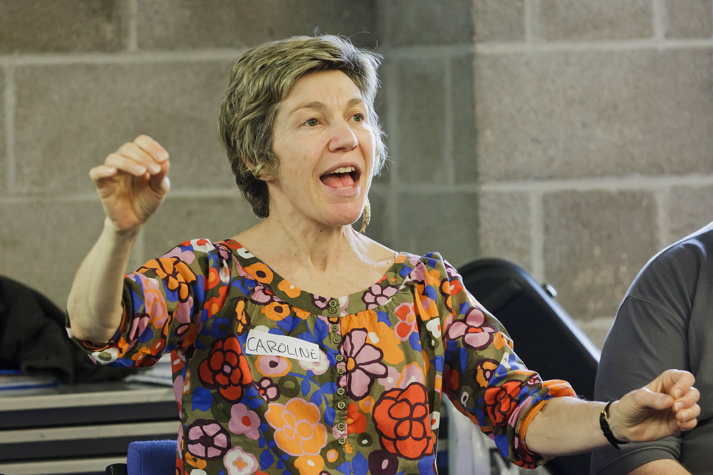 Close up of music teacher Caroline in full voice conducting the group with her hands.