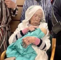An amusing picture of Marjorie, a member of Old Silk Works, dressed as Mary holding a baby Jesus doll and pointing her finger at him.