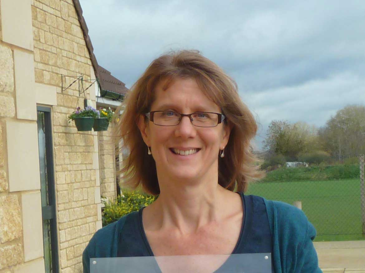 head and shoulders of Stephany outside a building with a green lawn in the background. Wearing blue-green top.
