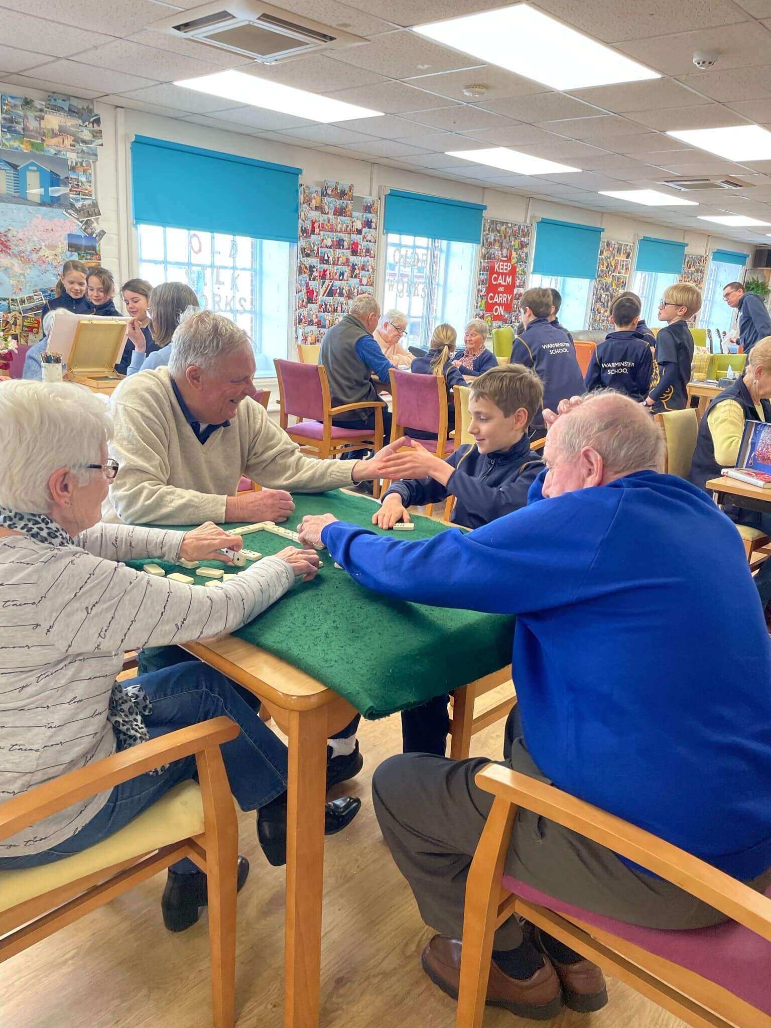 Ladies and gentlemen in Old Silk Works club, some are playing dominoes, some painting with school children interacting with them