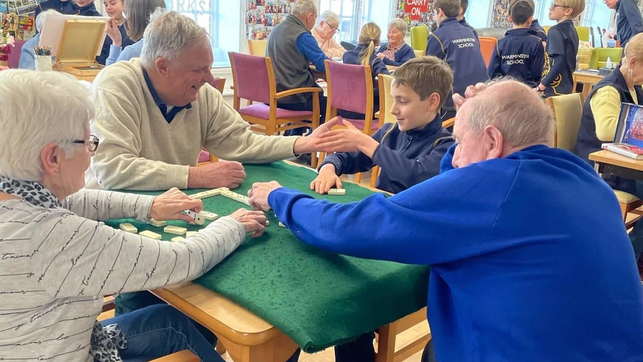 Ladies and gentlemen in Old Silk Works club, some are playing dominoes, some painting with school children interacting with them