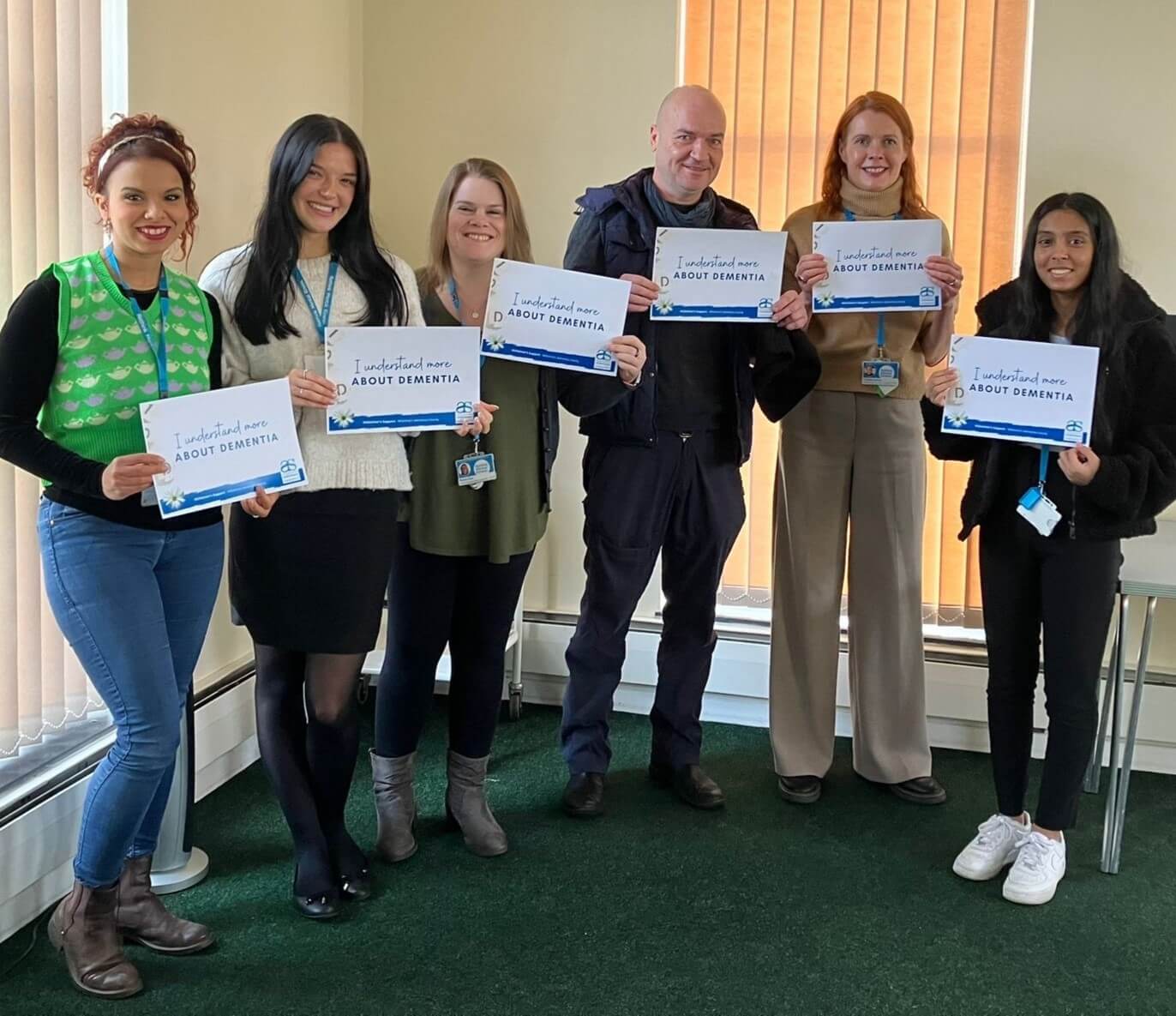 A group of volunteers from Rethink in Bath holding 'I Understand More' cards after their session