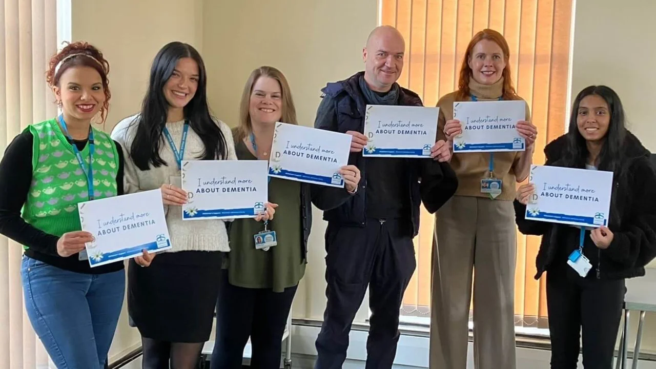 A group of volunteers from Rethink in Bath holding 'I Understand More' cards after their session