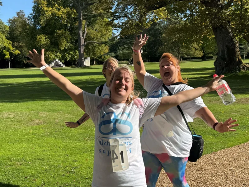 Three ladies in Alzheimer's Support t-shirts posing with their arms in their air at a sponsored walk Three ladies in Alzheimer's Support t-shirts posing with their arms in their air at a sponsored walk